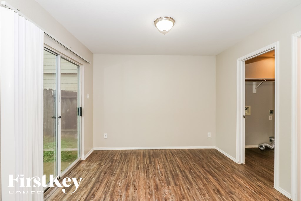 A room with wooden floors and white walls, with a sliding glass door on the left.
