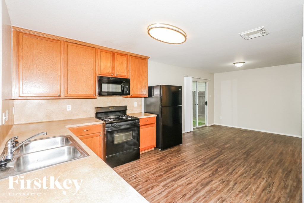 A kitchen with wooden cabinets and a black refrigerator.