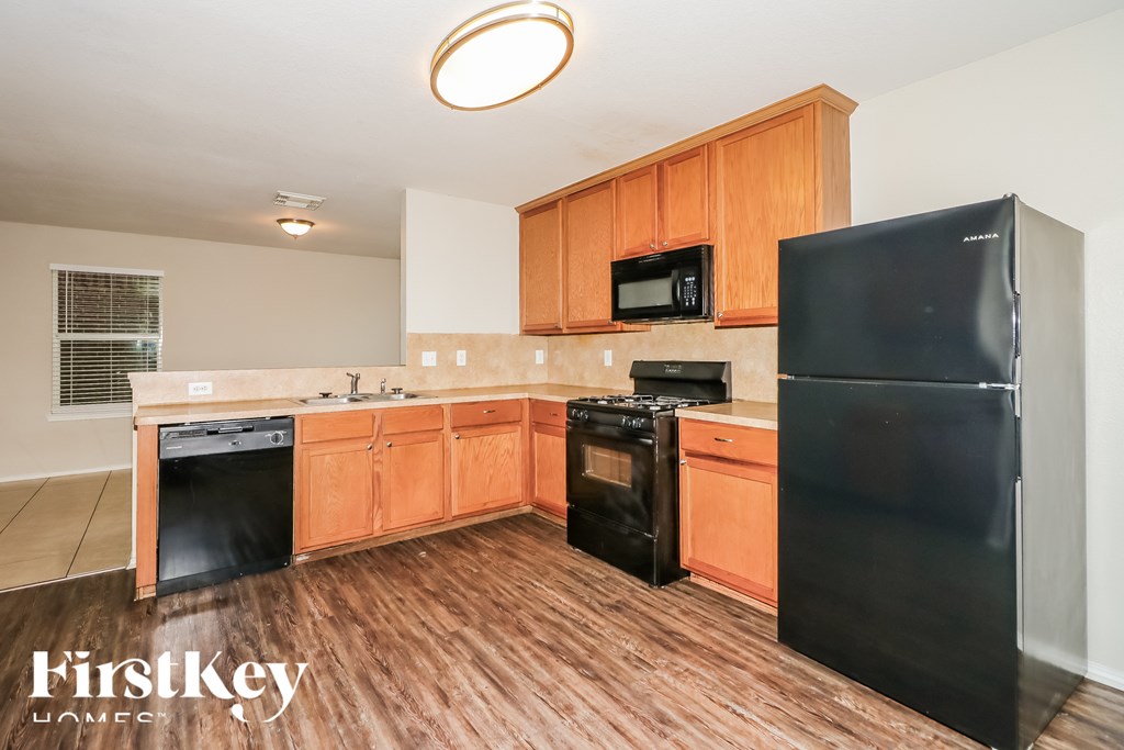 A kitchen with wooden cabinets and a black refrigerator.