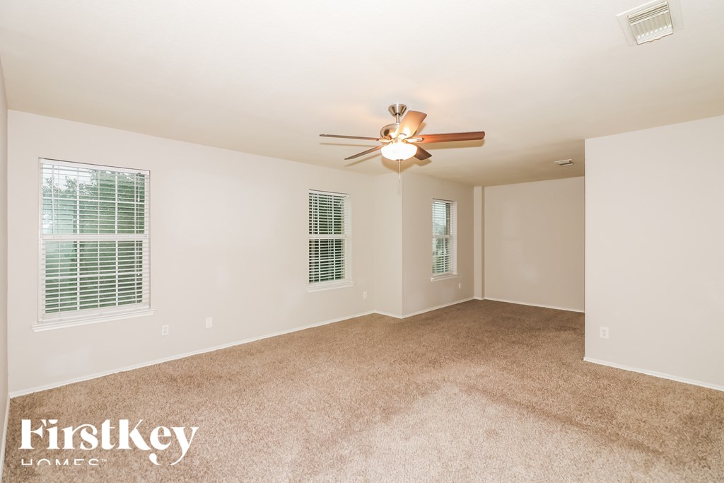 A room with a ceiling fan and two windows.