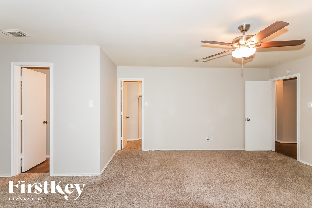A spacious room with a ceiling fan and beige carpeting.