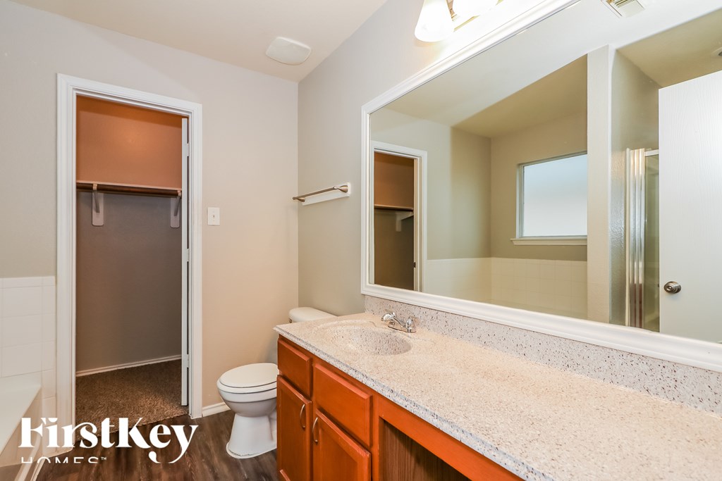 A bathroom with a toilet, sink and mirror.