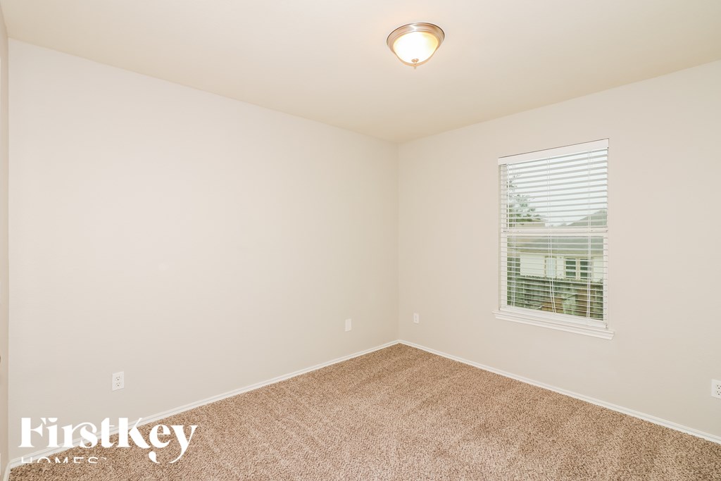 A room with a carpet floor and a window with blinds.