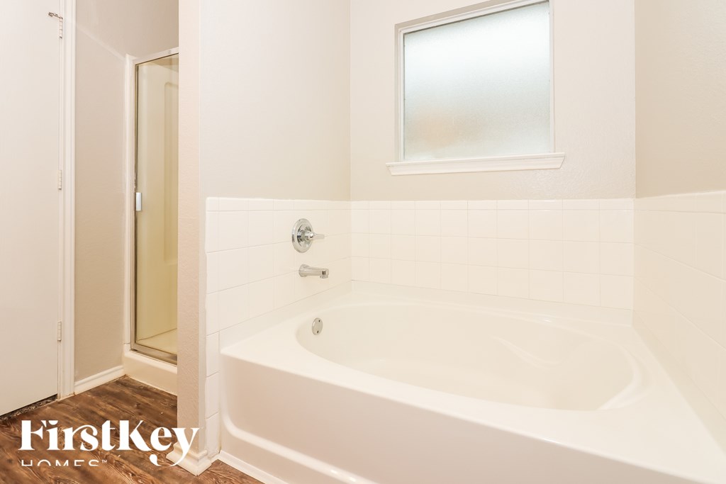 A white bathroom with a tub and a window.