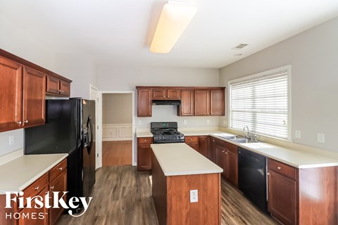 a kitchen with wooden cabinets and black appliances and white counter tops