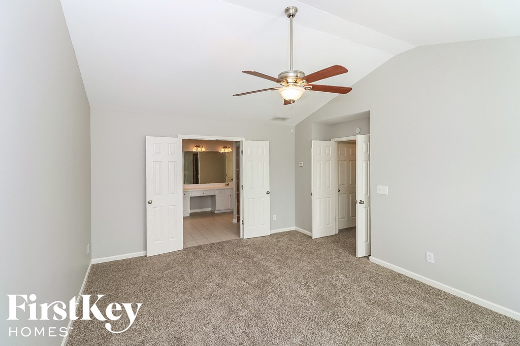 a master bedroom with a ceiling fan and a carpeted floor