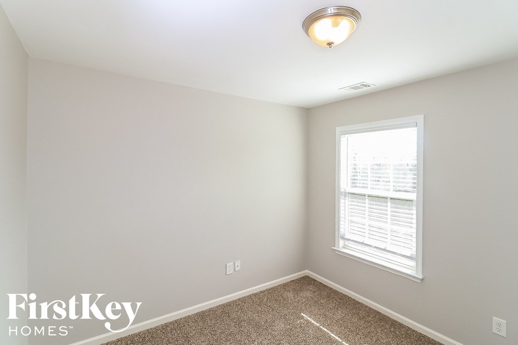 a bedroom with a window and a carpeted floor