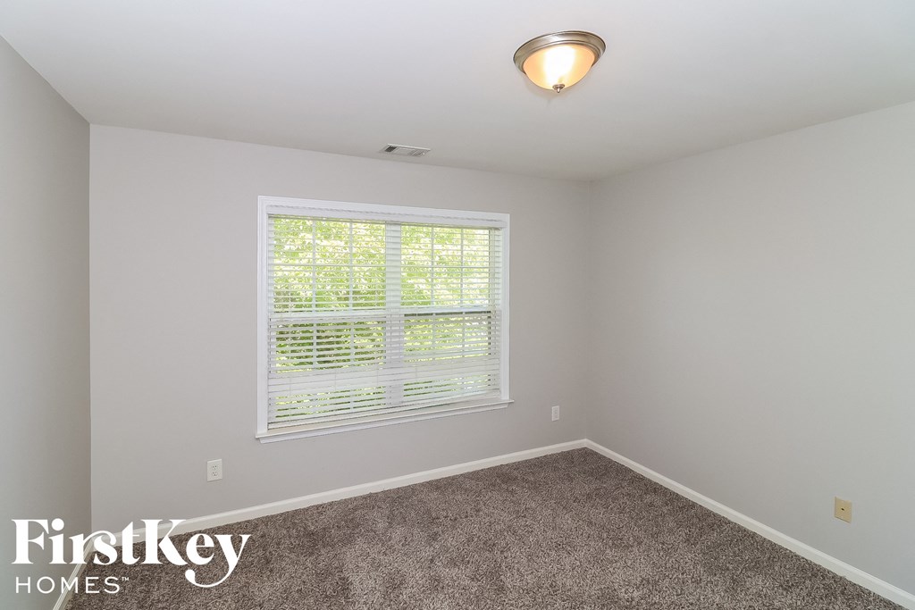 the second bedroom has a large window and carpeted flooring