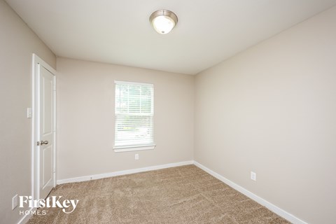 a bedroom with carpet and a white door and a window