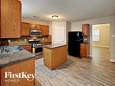 A kitchen with wooden cabinets and a black refrigerator.