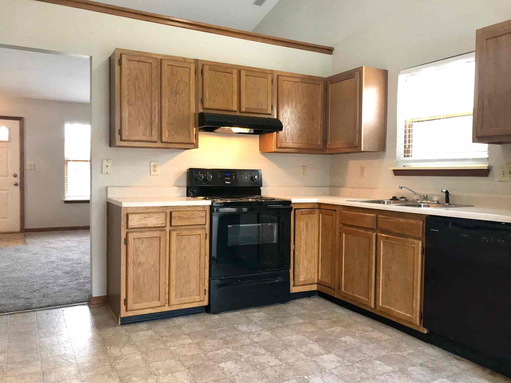 A kitchen with wooden cabinets and a black oven.