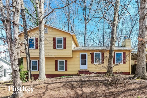 a yellow house in the woods with trees