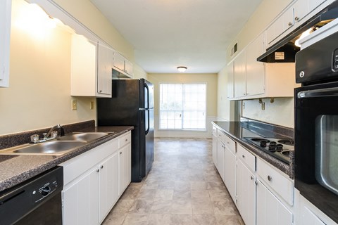 A kitchen with black appliances and white cabinets.