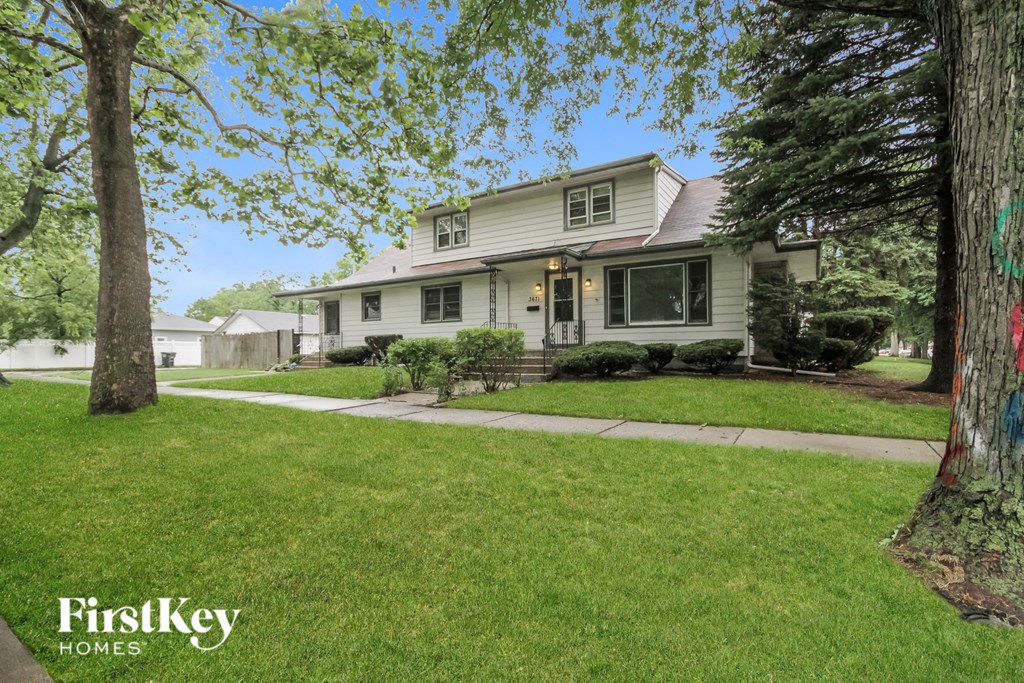 a white house with a lawn and trees in front of it