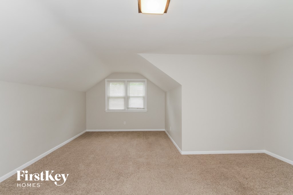 a bedroom with white walls and carpet and a window