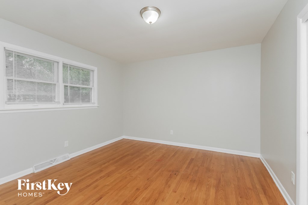 the second bedroom has a hardwood floor and a large window