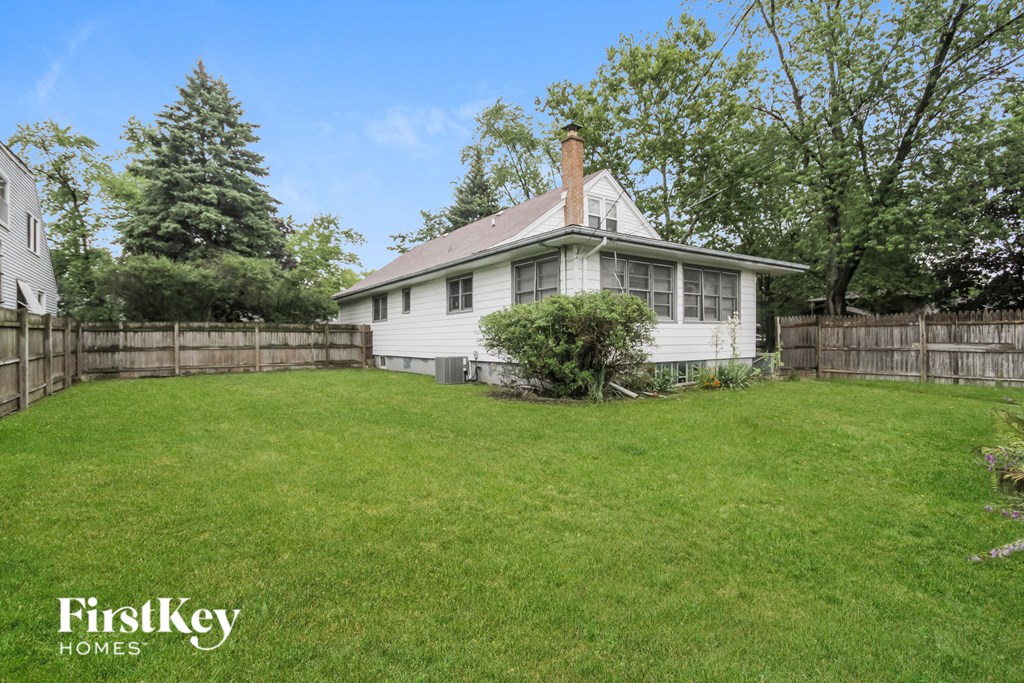 a small white house with a yard and a fence
