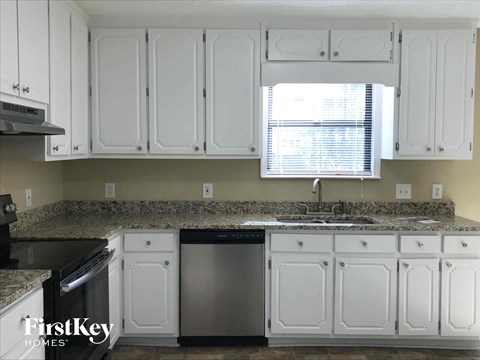 A kitchen with white cabinets and a granite countertop.