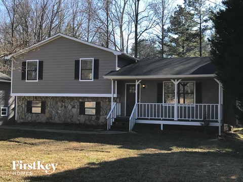 A house with a porch and a stone wall is shown.