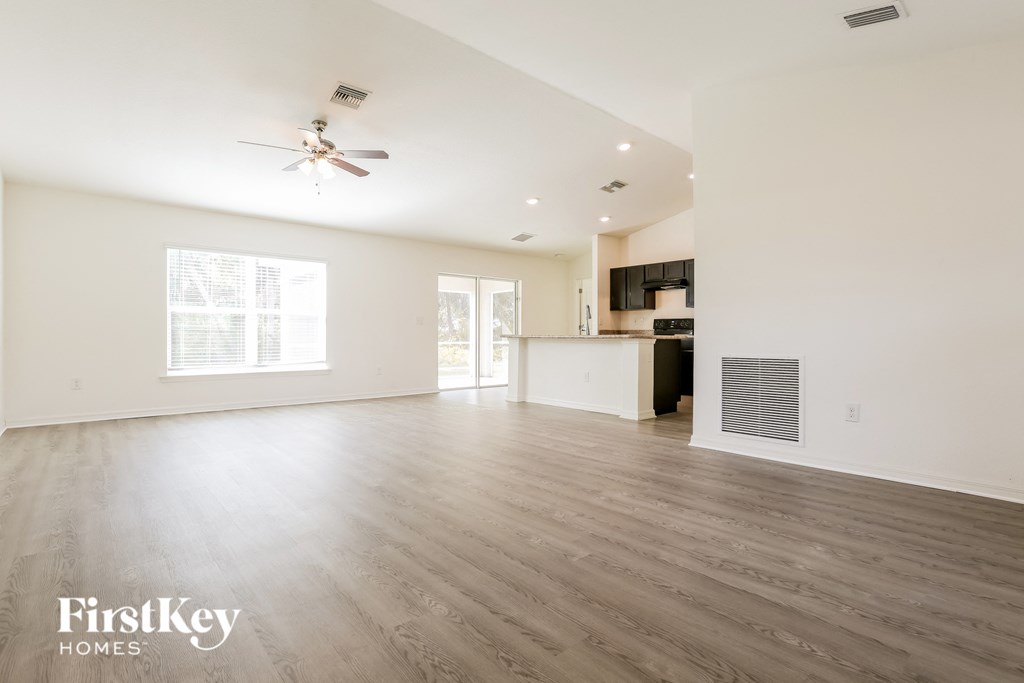 A spacious room with a ceiling fan and wooden flooring.