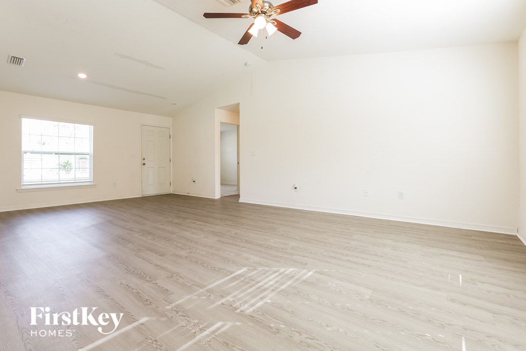 A spacious room with a ceiling fan and wooden flooring.