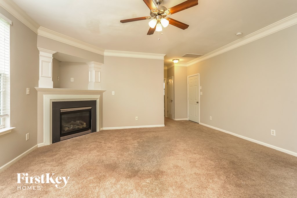 A spacious room with a fireplace and a ceiling fan.