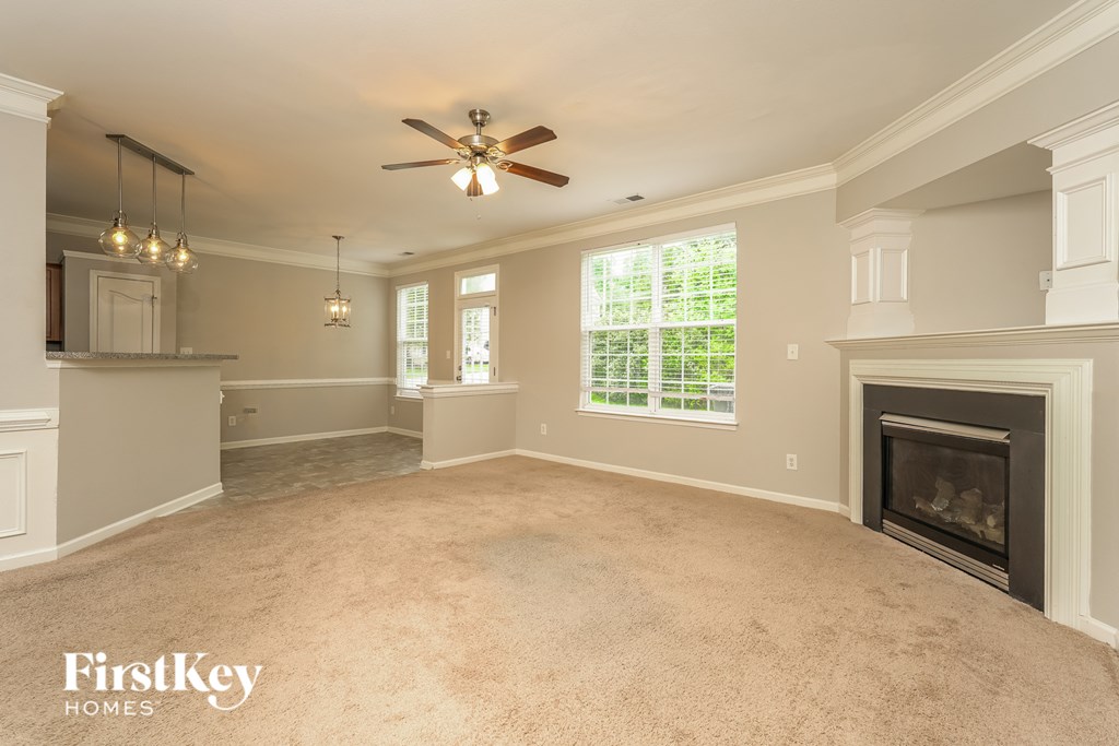 A spacious living room with a fireplace and a ceiling fan.