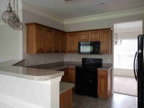 A kitchen with a black oven and wooden cabinets.