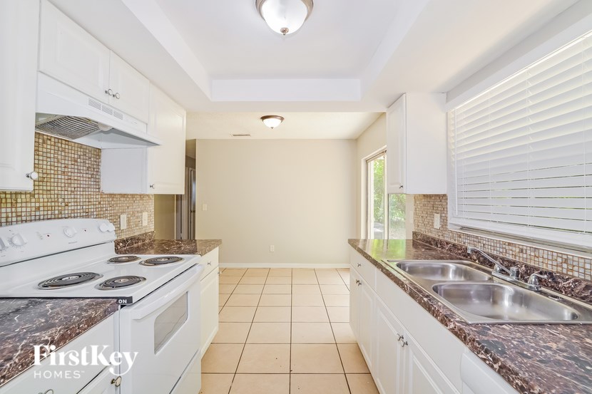 A kitchen with a white stove top oven and a marble counter top.