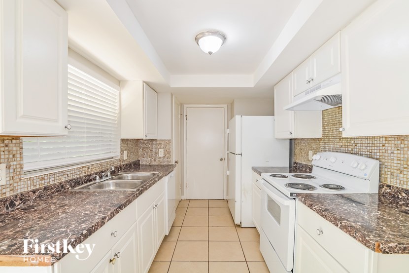 A kitchen with white cabinets and a marble countertop.