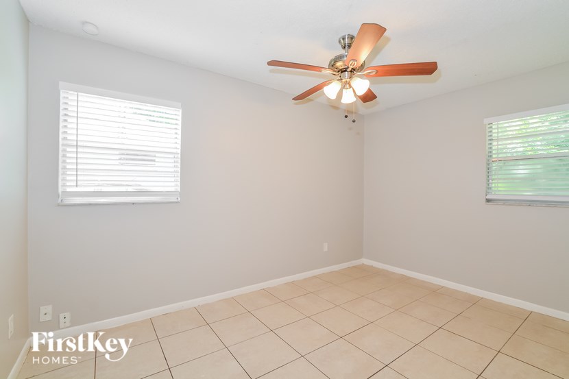 A room with a ceiling fan and two windows.