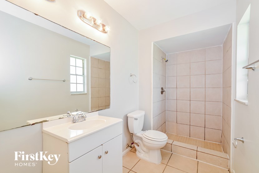 A bathroom with a white toilet, sink, and tiled walls.