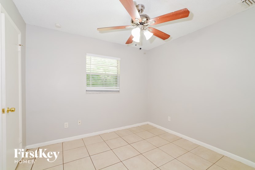 A room with a ceiling fan and a window with blinds.
