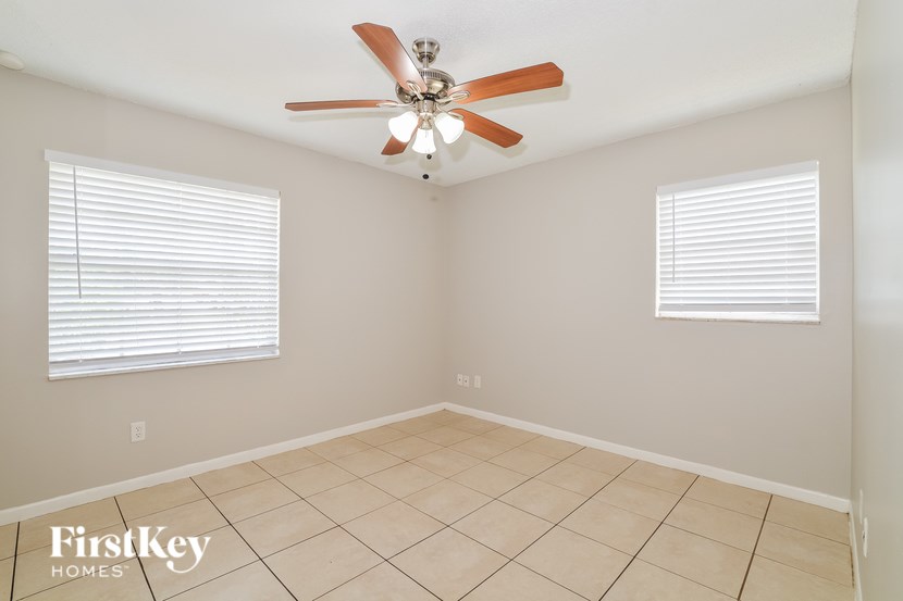 A room with a ceiling fan and two windows with blinds.