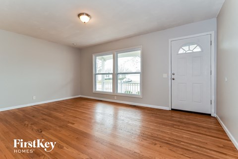 the living room of an empty house with wood floors and a white door