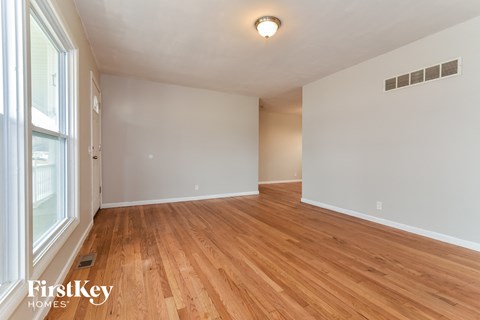 the living room and dining room with hardwood flooring and a large window