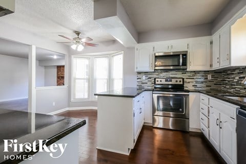 a kitchen with white cabinets and stainless steel appliances and a ceiling fan