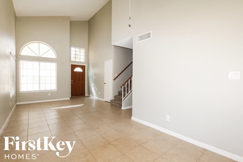 a large empty living room with a staircase and a large window