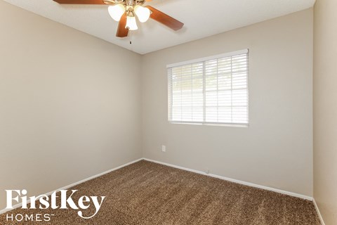 the bedroom has a ceiling fan and beige carpet and a window