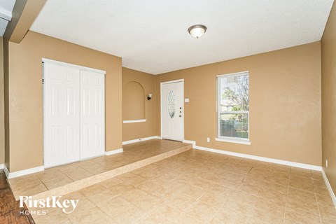 A room with a white door and a window with a view of trees.