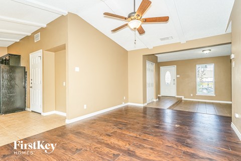 A spacious room with wooden floors and a ceiling fan.