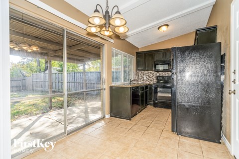 A kitchen with a black refrigerator and a glass door.