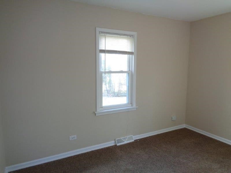 an empty room with a window and a carpet