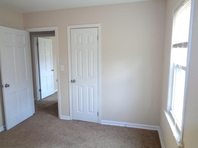 an empty bedroom with two doors and a carpeted floor