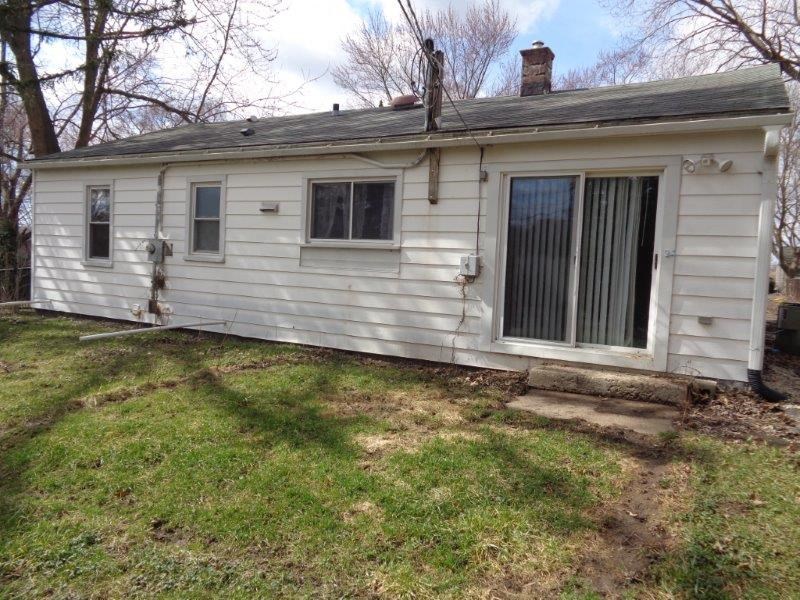 a small white house with a yard and some trees