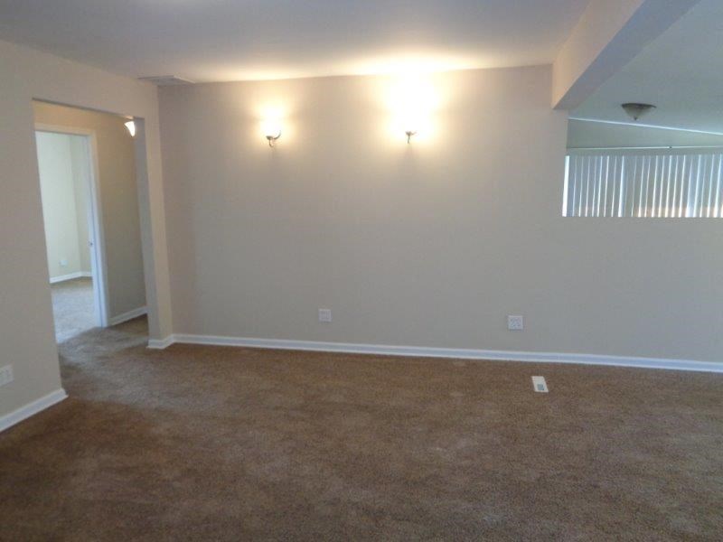 an empty living room with two lights on the wall