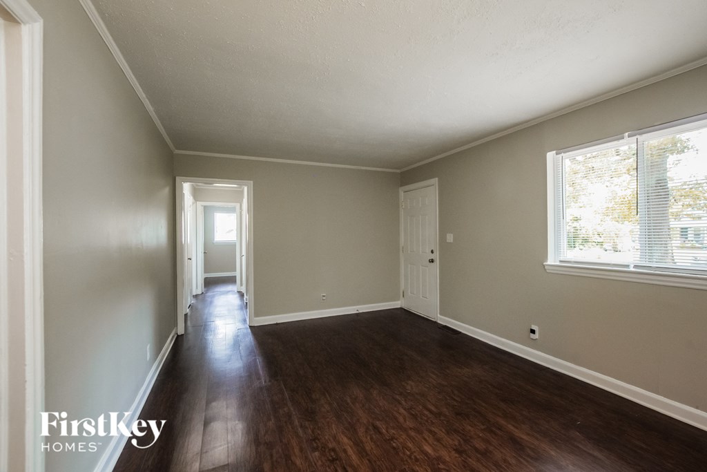 an empty living room with wood floors and a window