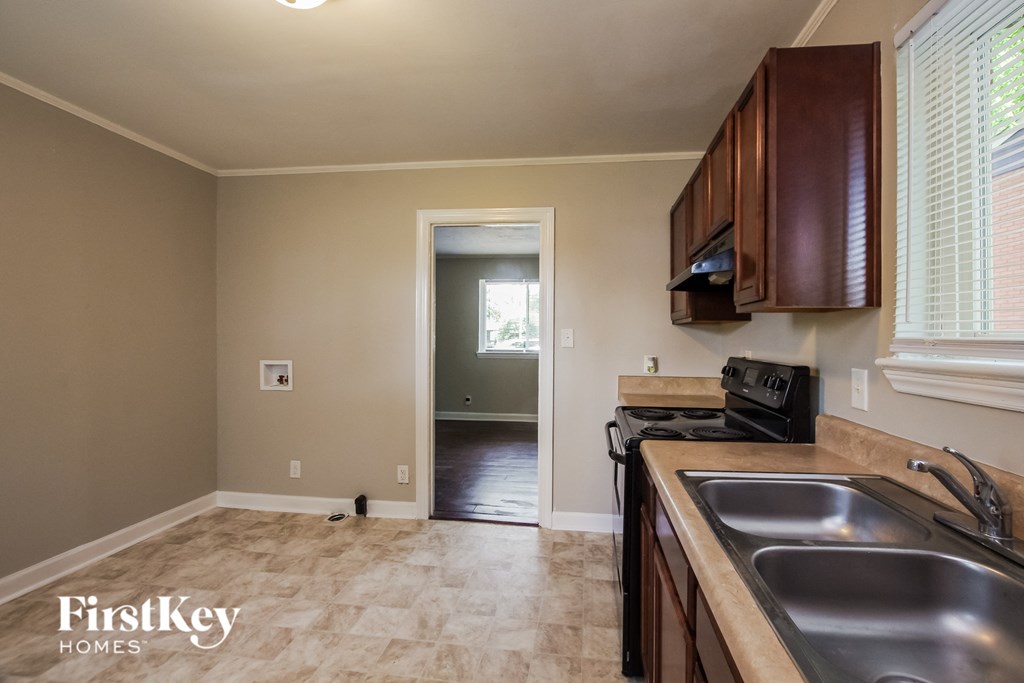 a kitchen with a sink and a stove and a door to a hallway