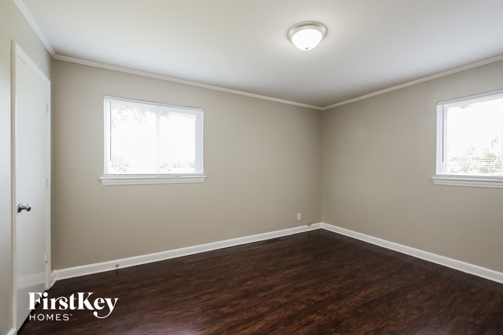 an empty room with wood flooring and two windows
