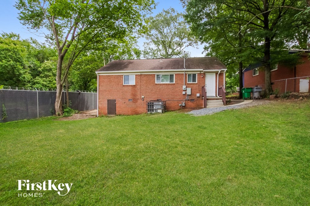 the back of a brick house with a yard and a fence